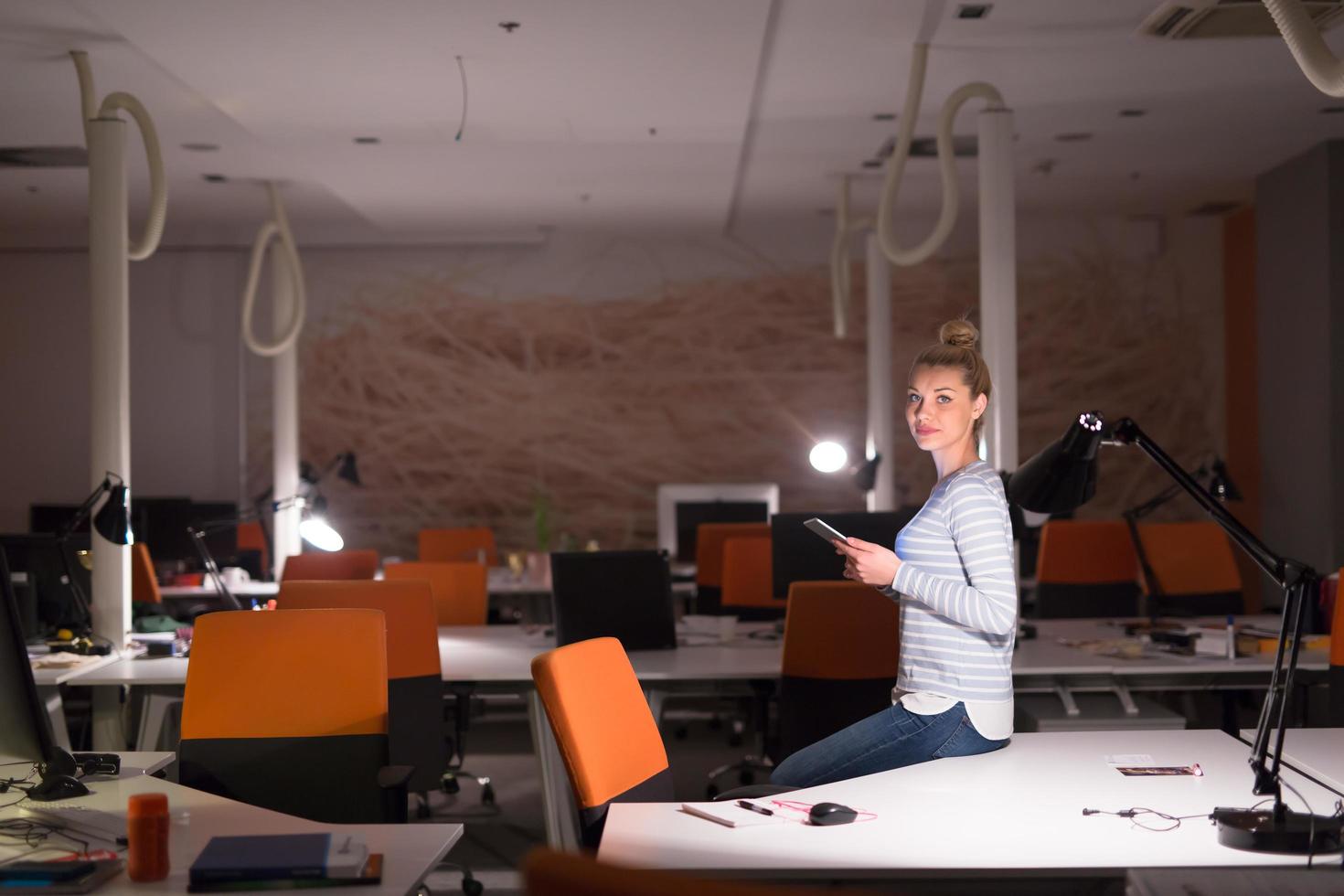 woman working on digital tablet in night office photo