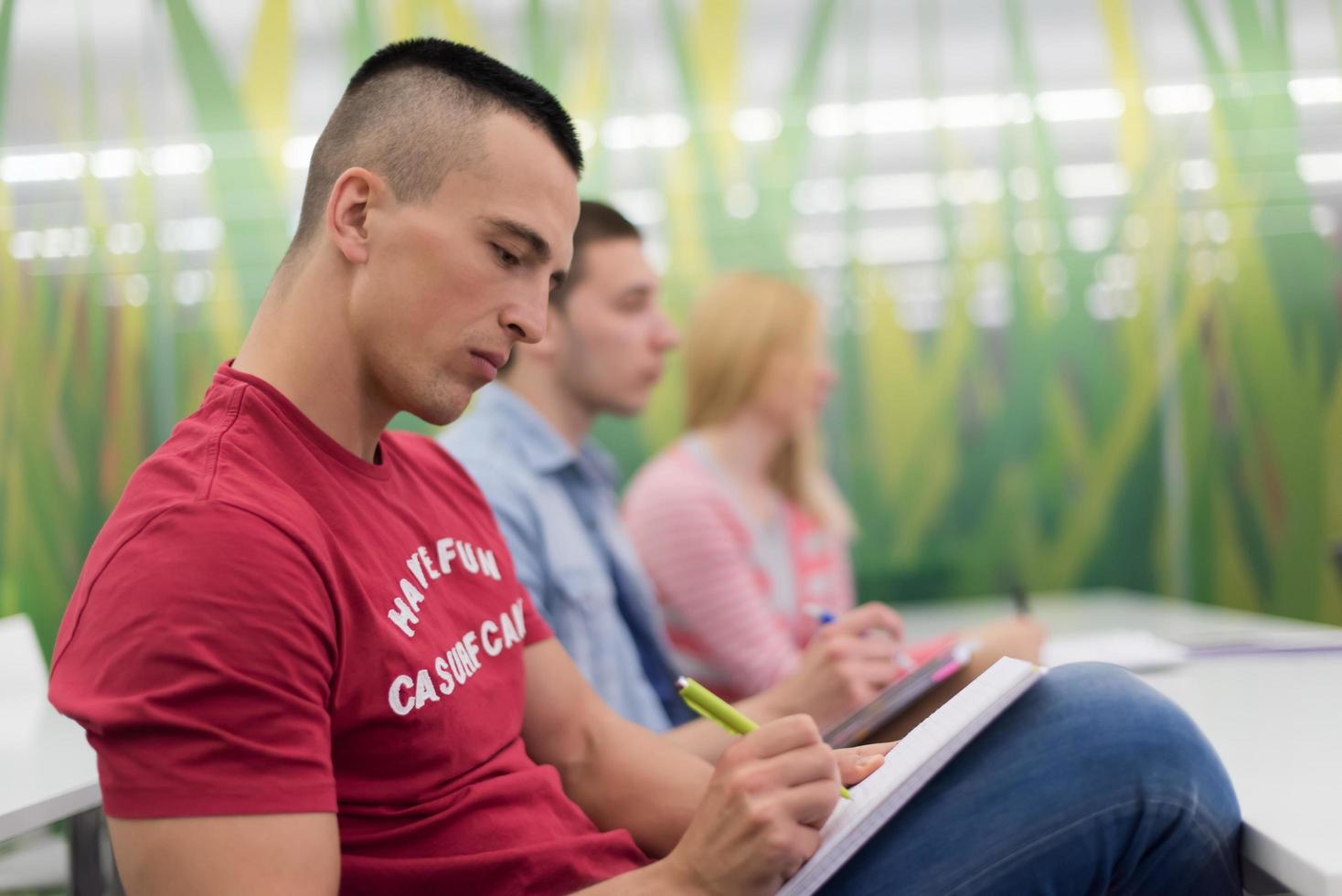 male student taking notes in classroom photo