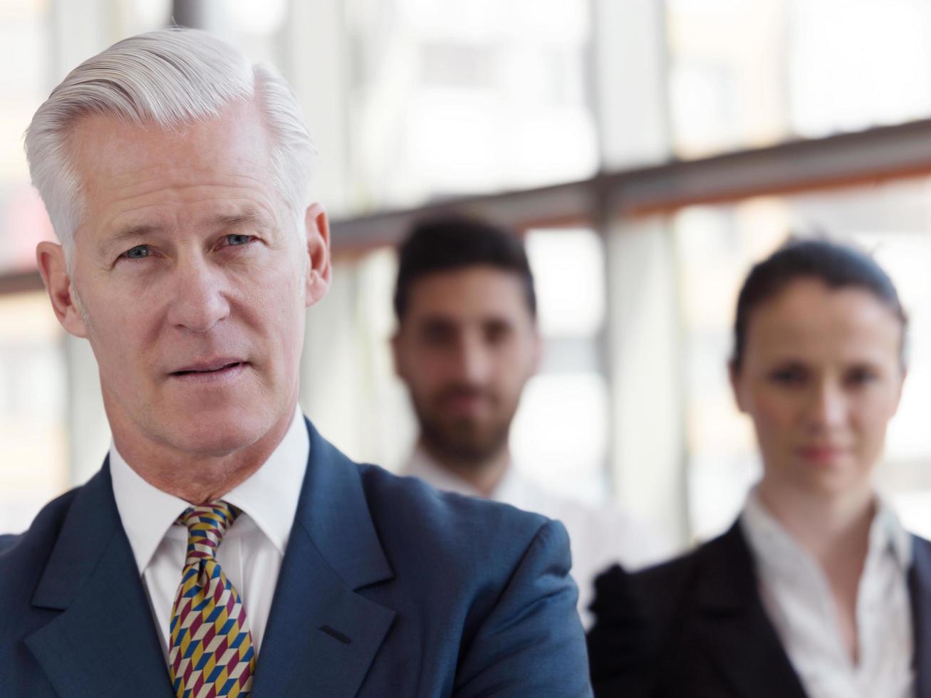 portrait of senior businessman as leader  with staff in background photo