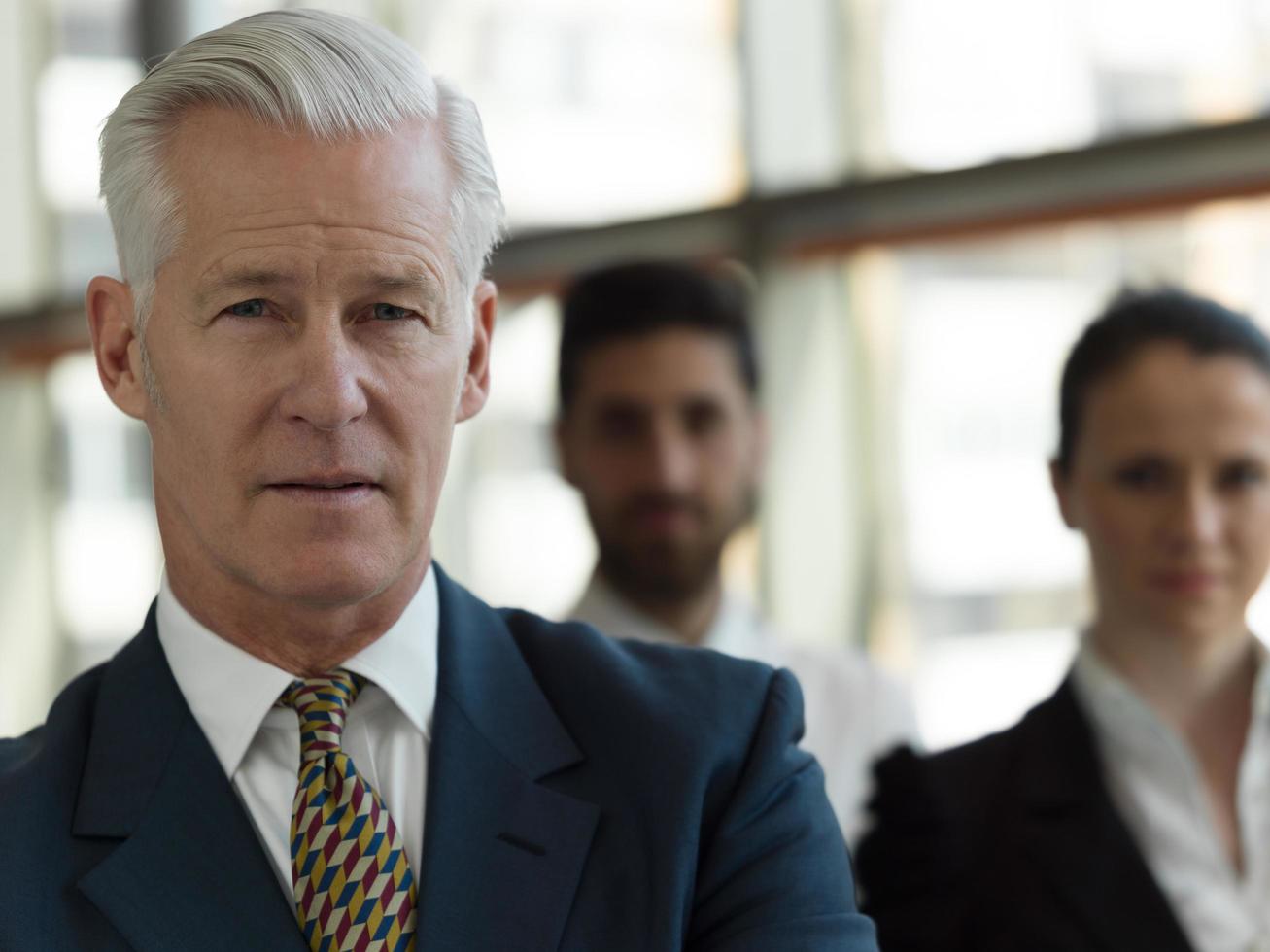 portrait of senior businessman as leader  with staff in background photo