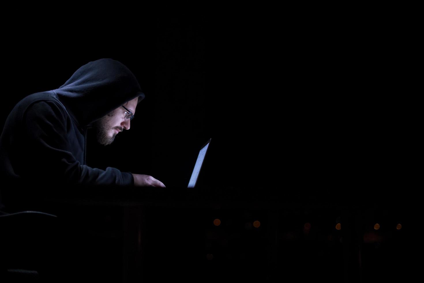 hacker using laptop computer while working in dark office photo