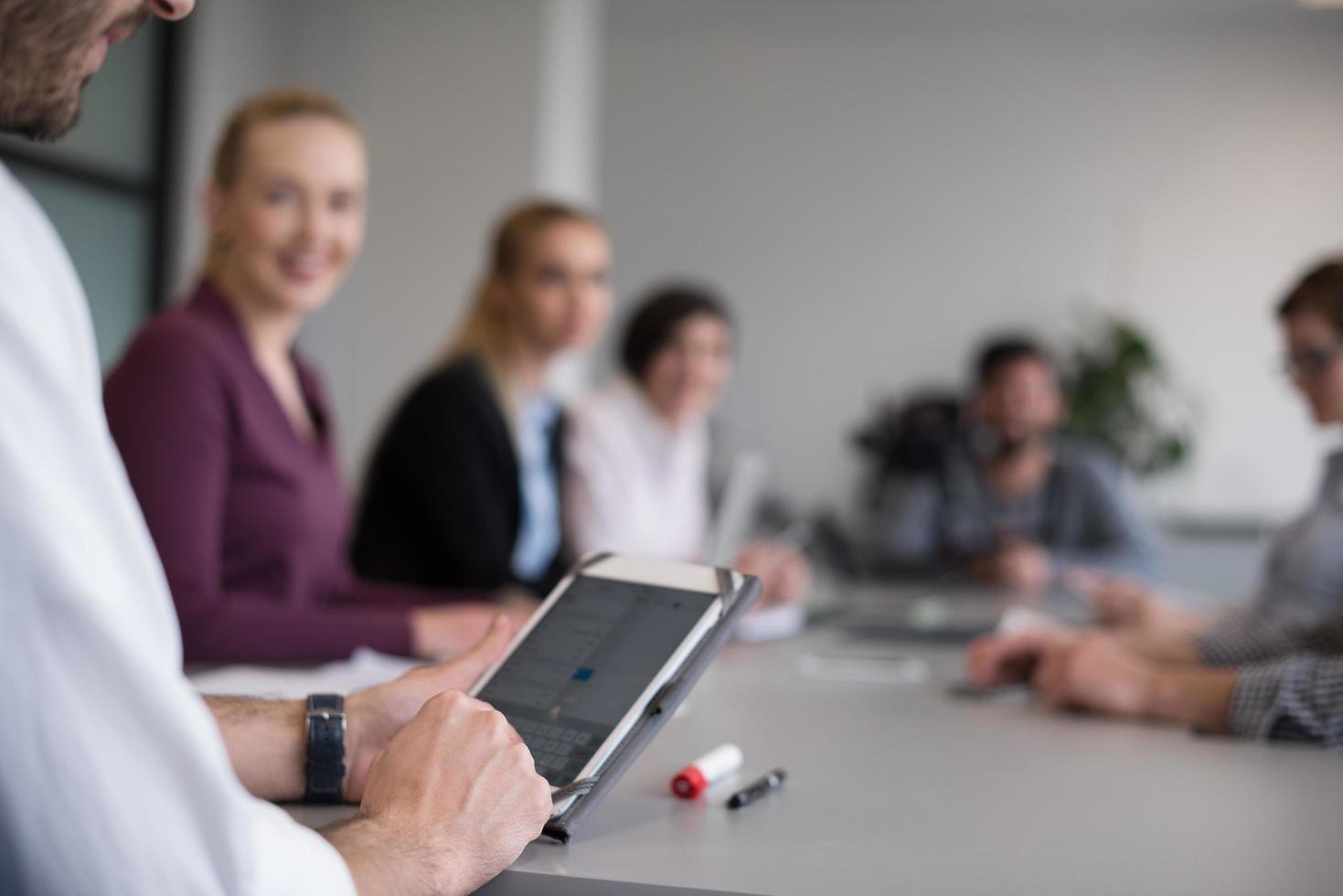 Cerca de las manos de un hombre de negocios usando una tableta en una reunión foto