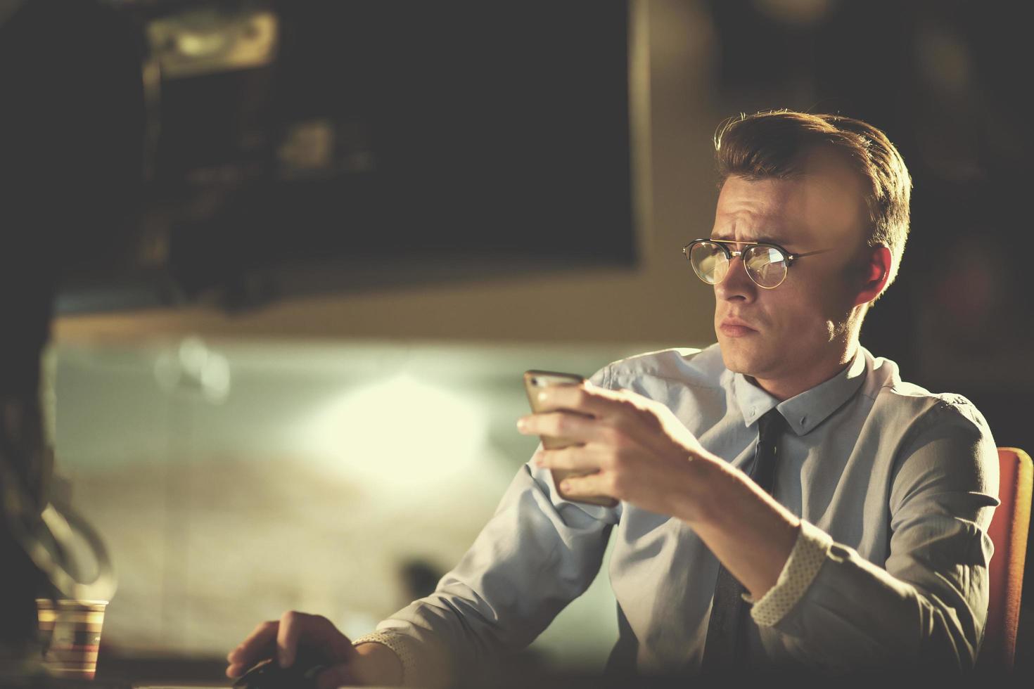 man using mobile phone in dark office photo