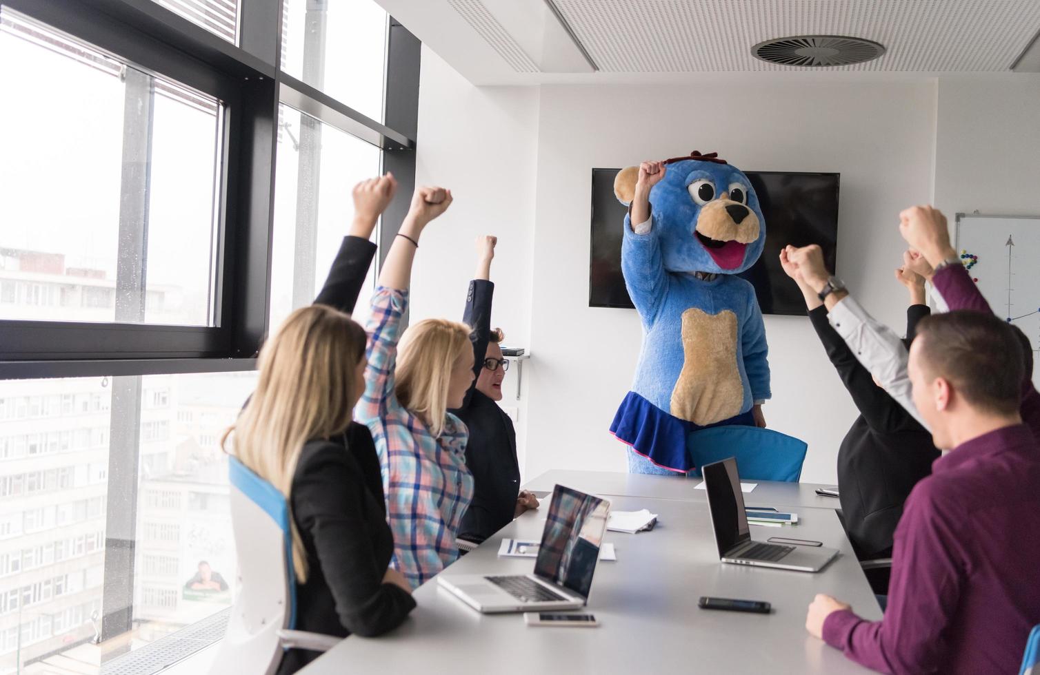 boss dresed as bear having fun with business people in trendy office photo