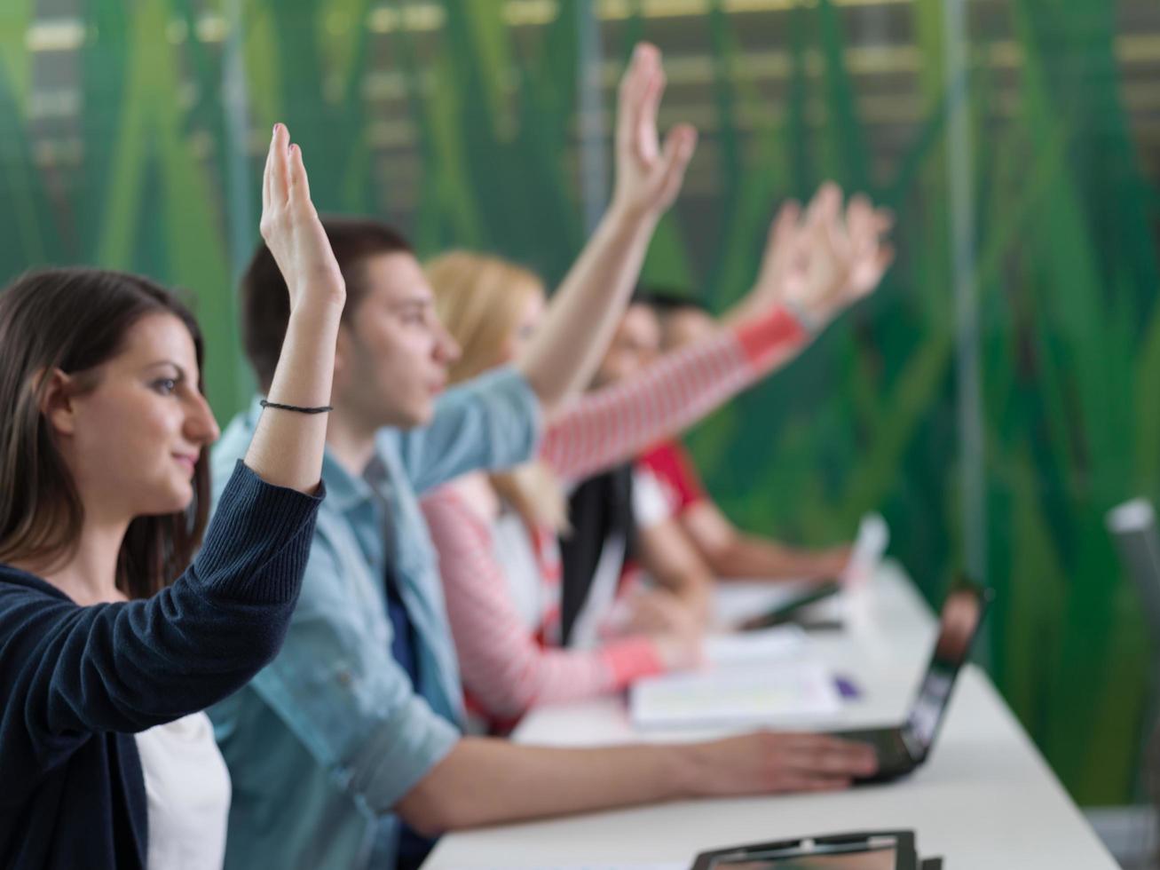 grupo de estudiantes levantan la mano en clase foto