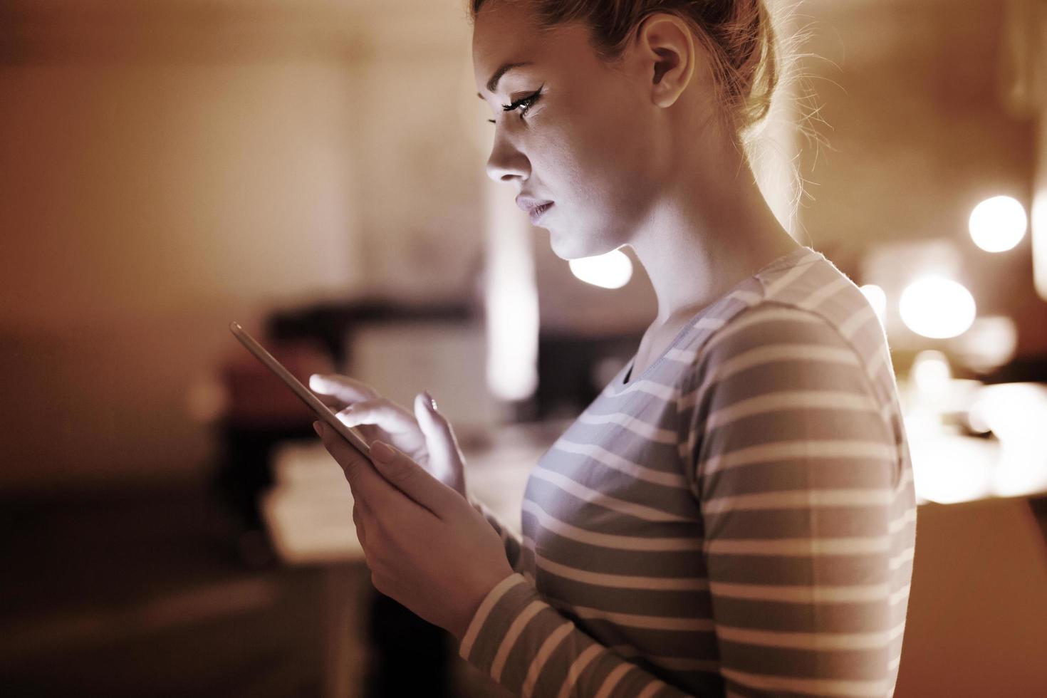 woman working on digital tablet in night office photo
