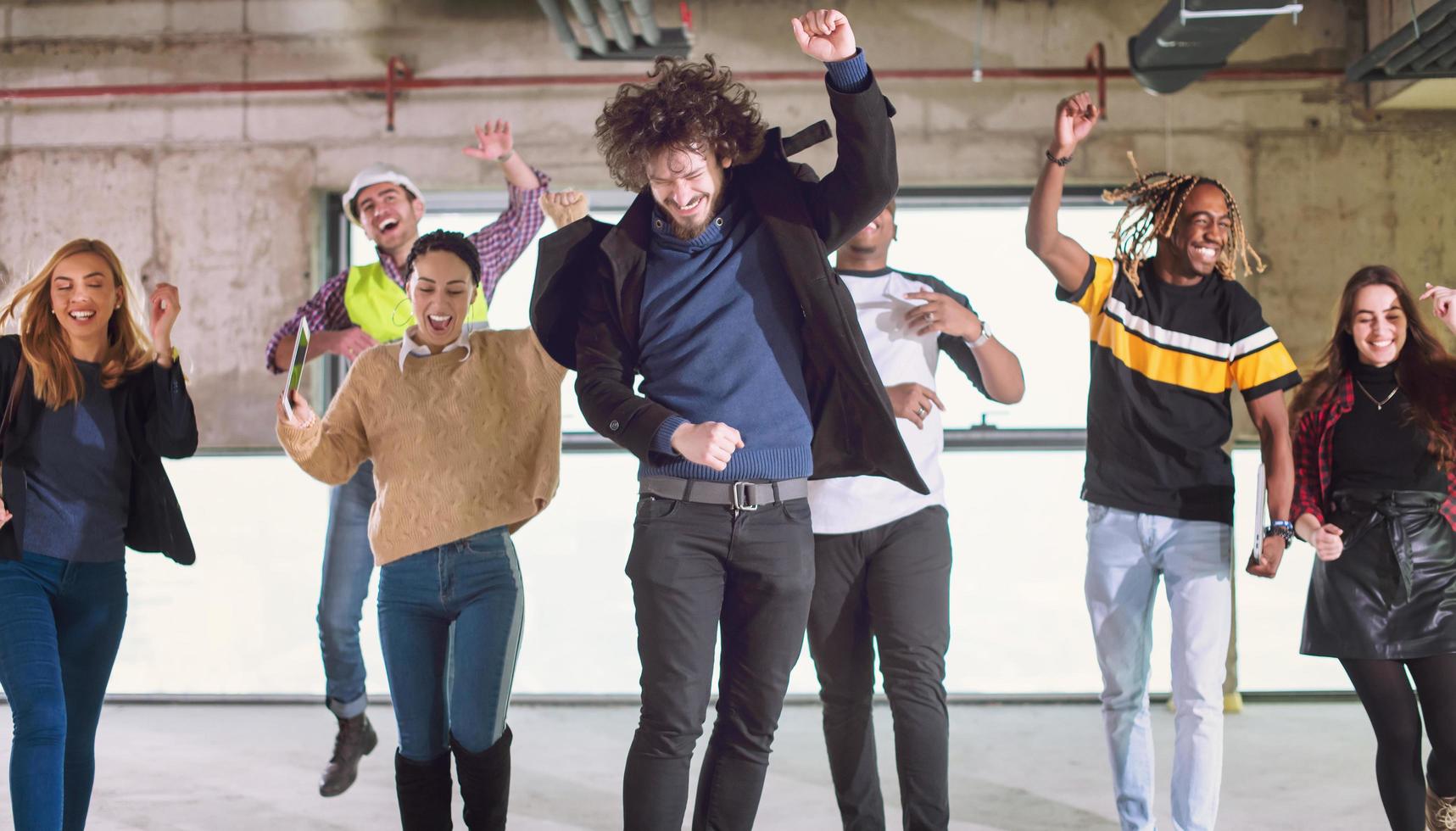 young multiethnic business people dancing in unfinished startup office photo