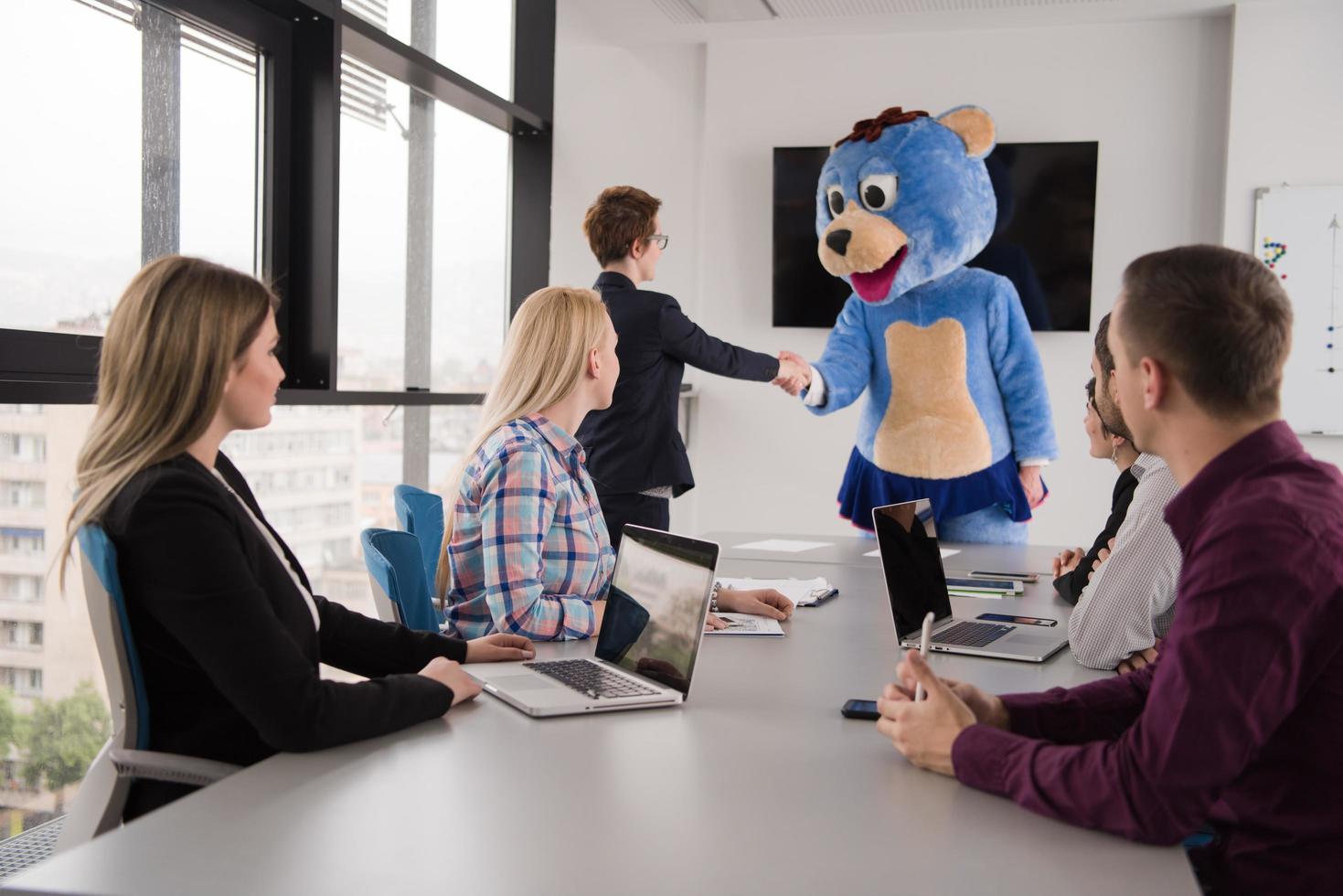 boss dresed as bear having fun with business people in trendy office photo
