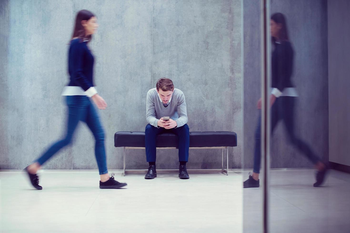 businessman using mobile phone while sitting on the bench photo