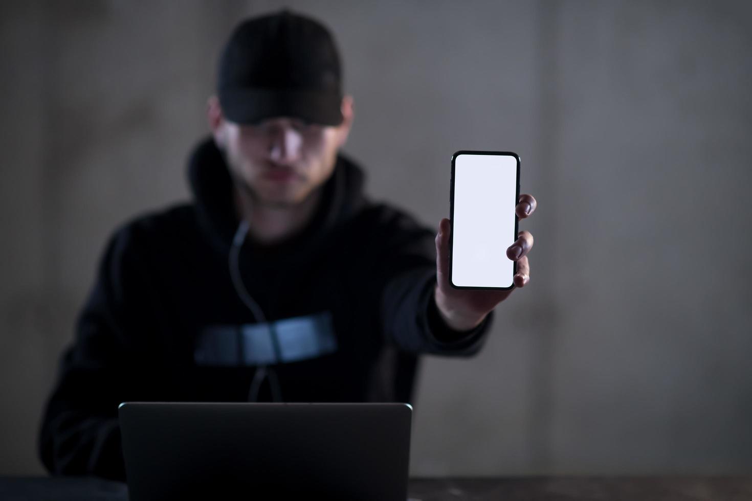 criminal hacker using laptop computer while working in dark office photo