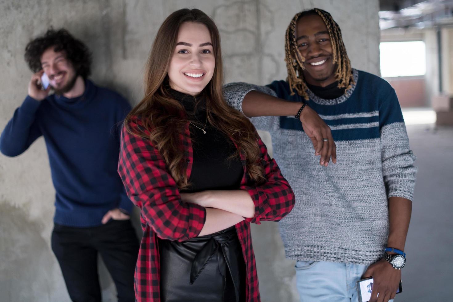 equipo de negocios multiétnico casual usando teléfonos móviles frente a un muro de hormigón foto