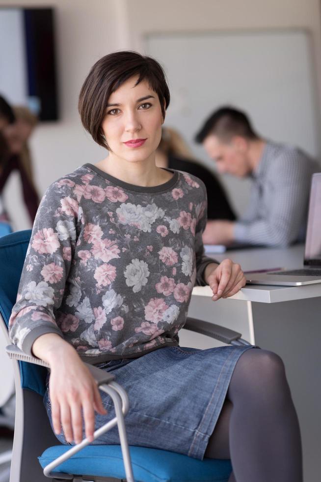 retrato de una joven mujer de negocios en la oficina con un equipo en una reunión en segundo plano foto