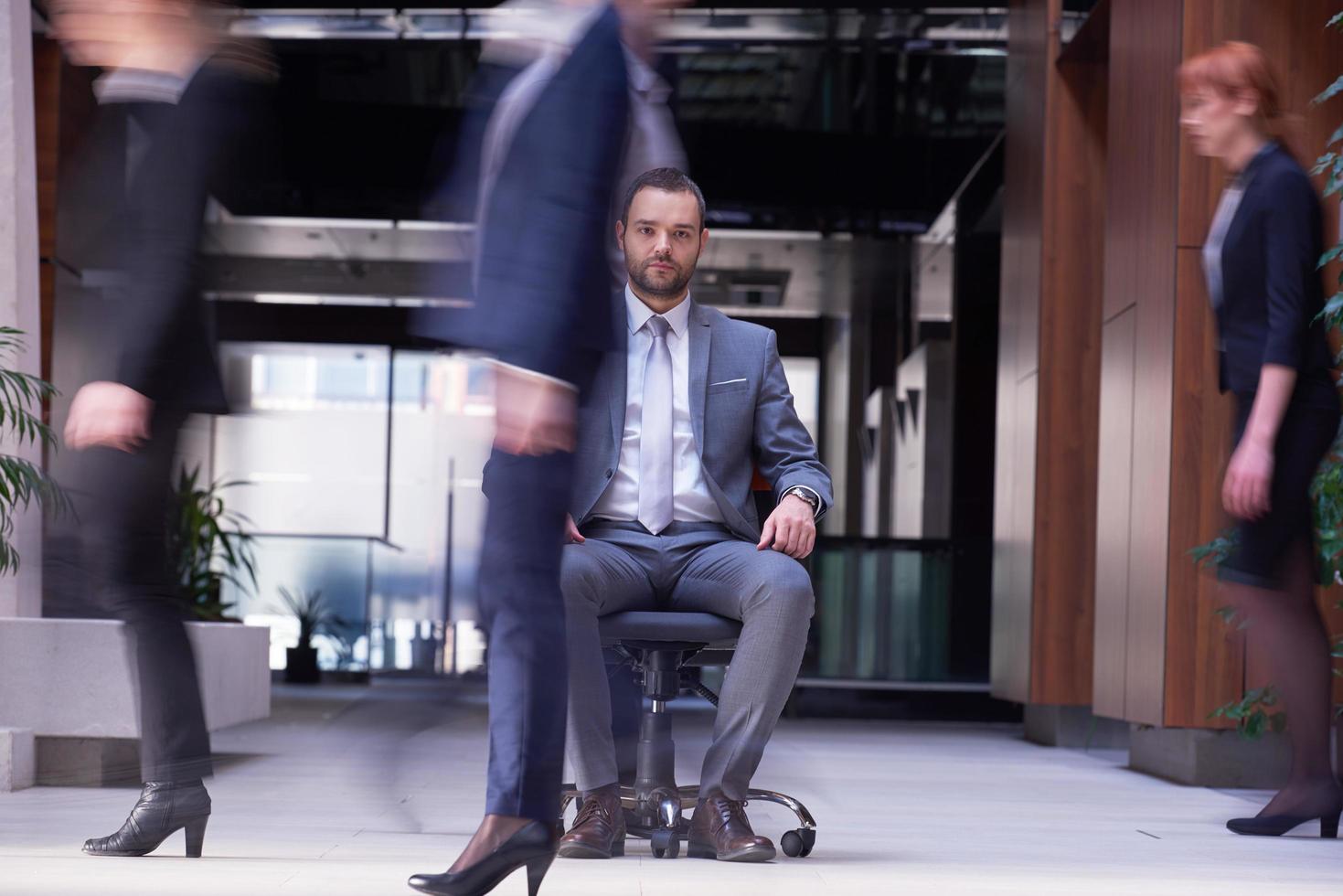 business man sitting in office chair, people group  passing by photo