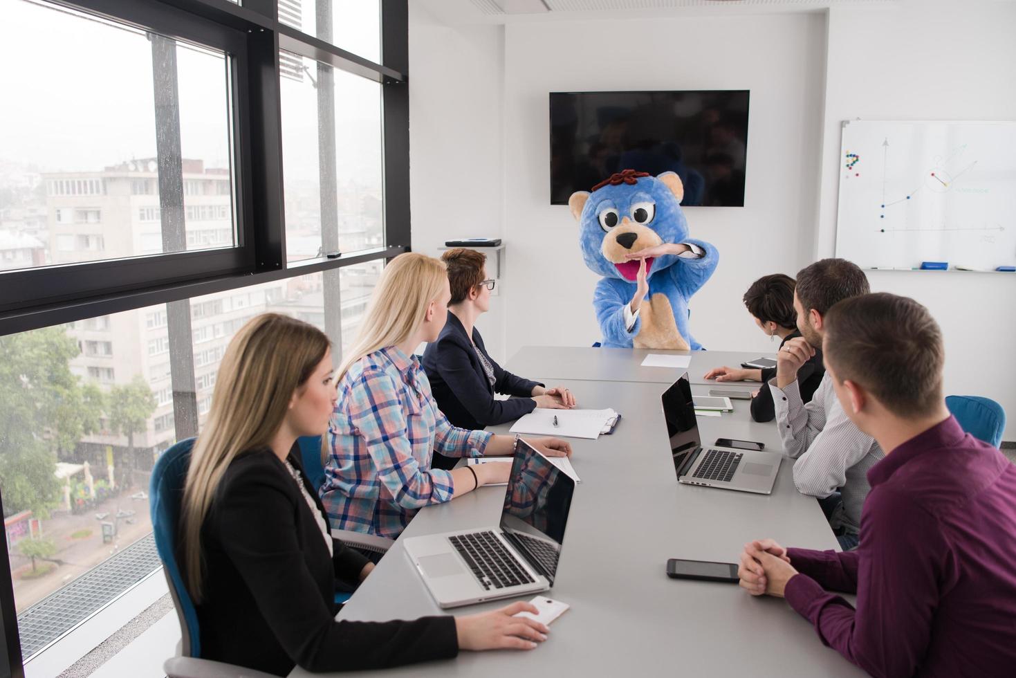 boss dresed as bear having fun with business people in trendy office photo