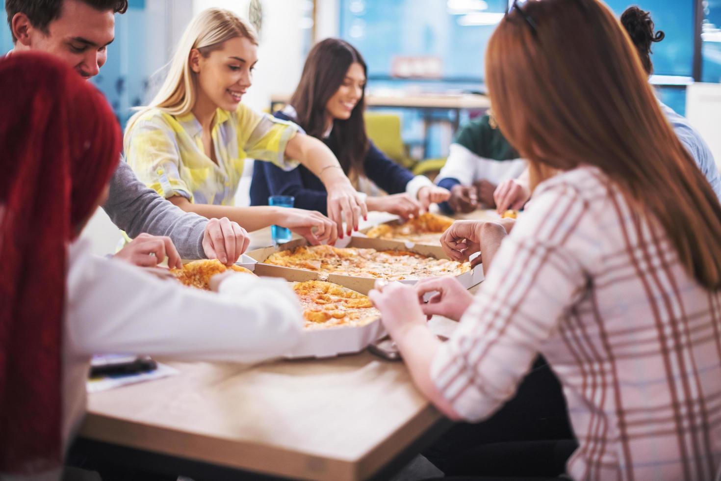 multiethnic business team eating pizza photo