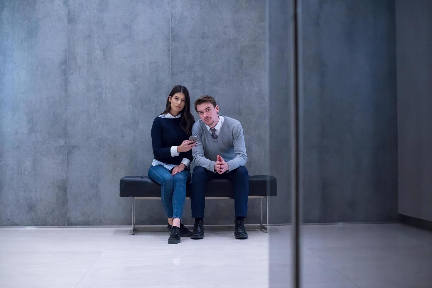 pareja de negocios usando teléfono móvil mientras está sentado en el banco foto