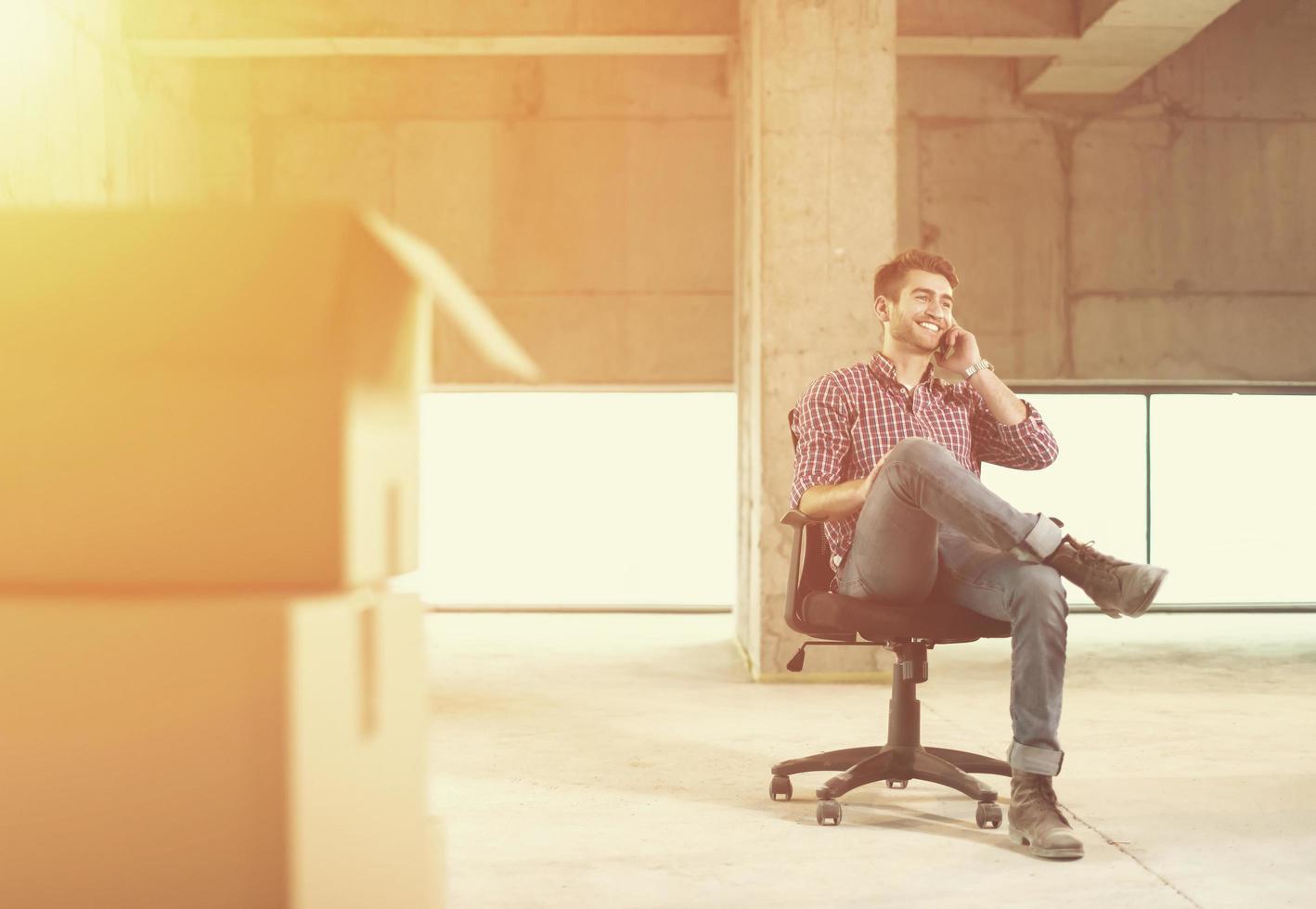 young casual businessman using mobile phone on construction site photo