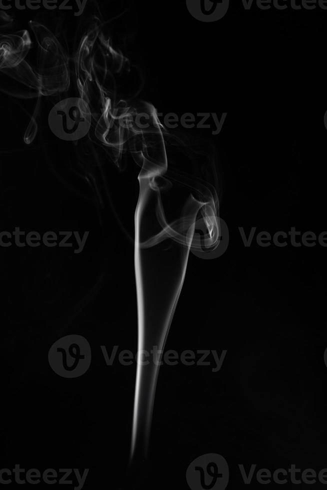 A single white smoke burn from incense, shot in studio with dark black background, for design and religion concept photo