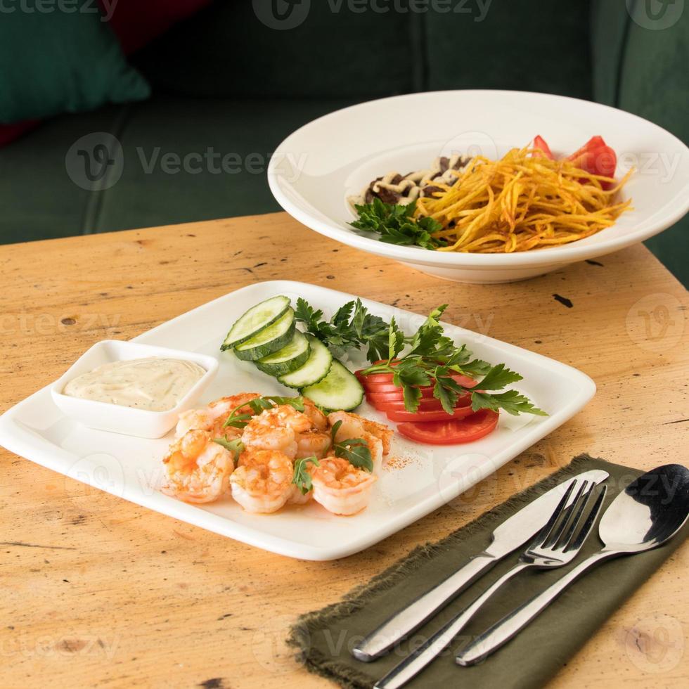 una mesa con comidas con hummus, camarones, verduras y carne de res foto