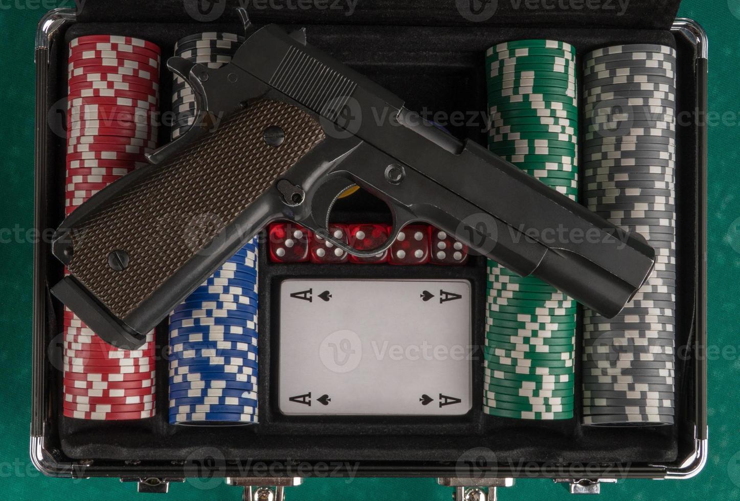 una toma superior de un arma en una caja de póquer abierta en un tablero verde. foto