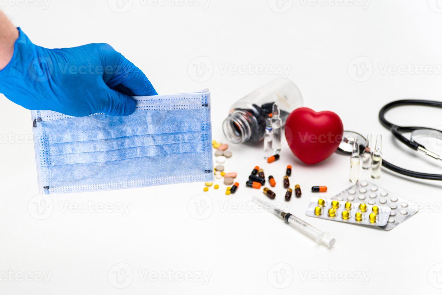 un primer plano de la mano de una persona con guantes que sostienen máscaras médicas y medicamentos en una mesa foto