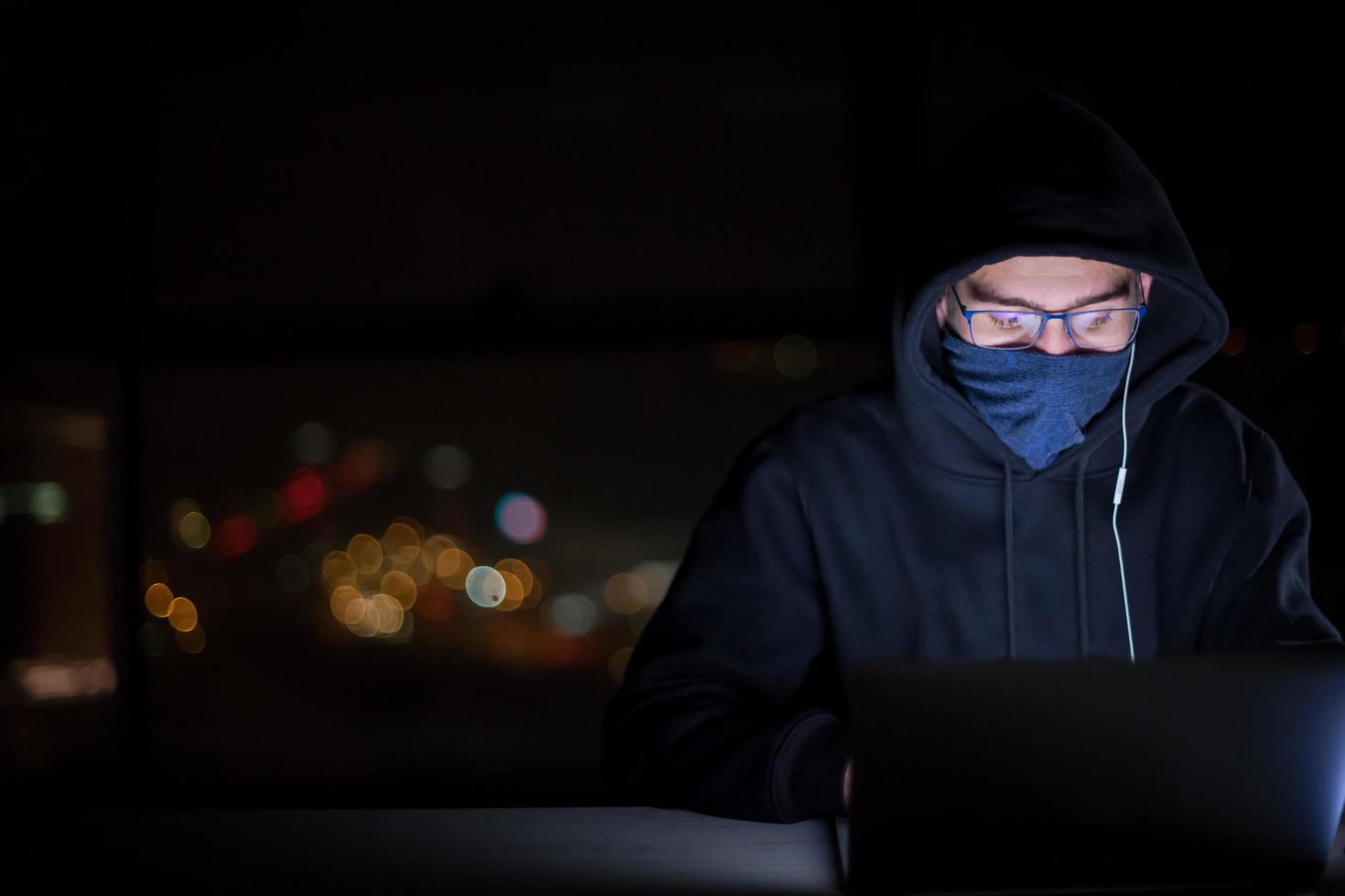 hacker using laptop computer while working in dark office photo