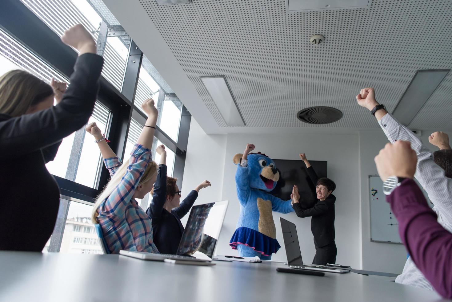 boss dresed as bear having fun with business people in trendy office photo