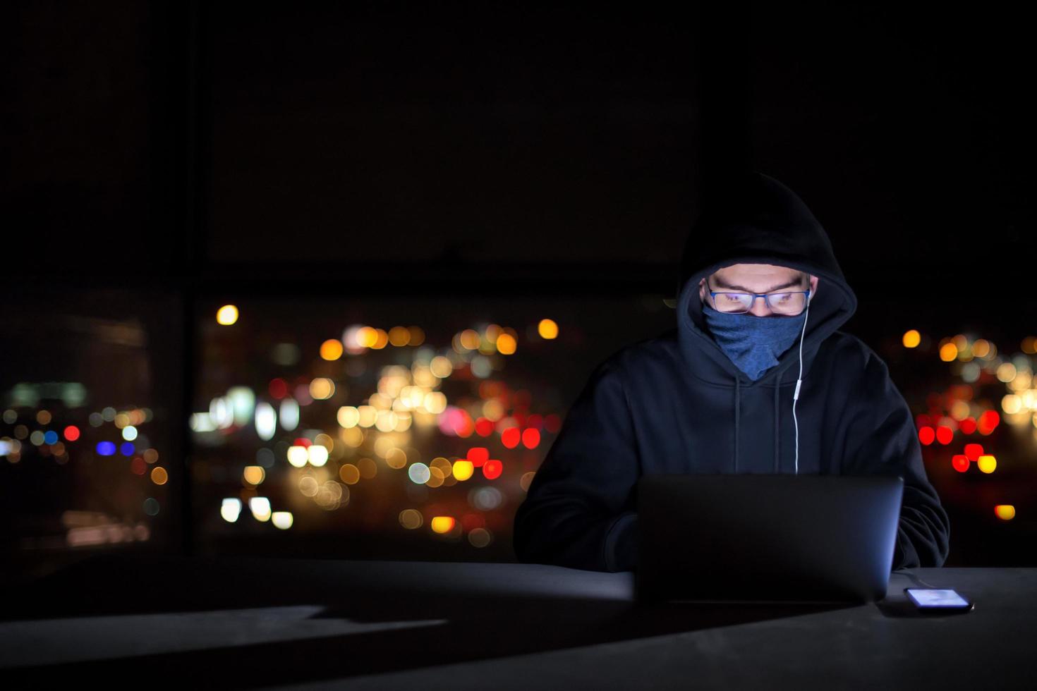 hacker using laptop computer while working in dark office photo