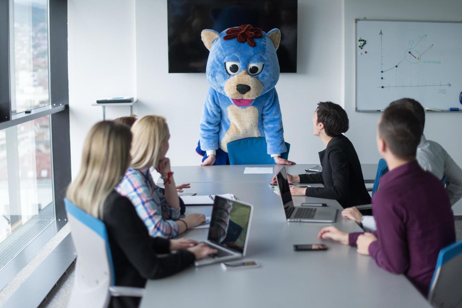 boss dresed as bear having fun with business people in trendy office photo