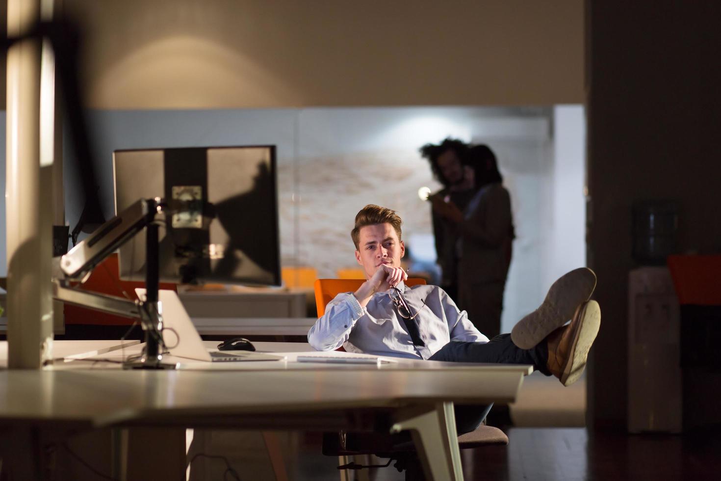 businessman sitting with legs on desk at office photo