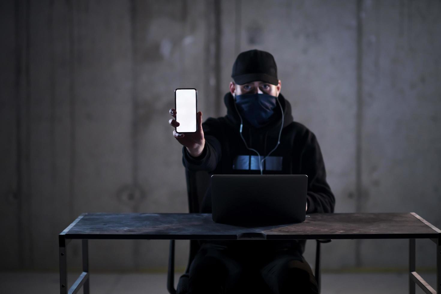 criminal hacker using laptop computer while working in dark office photo