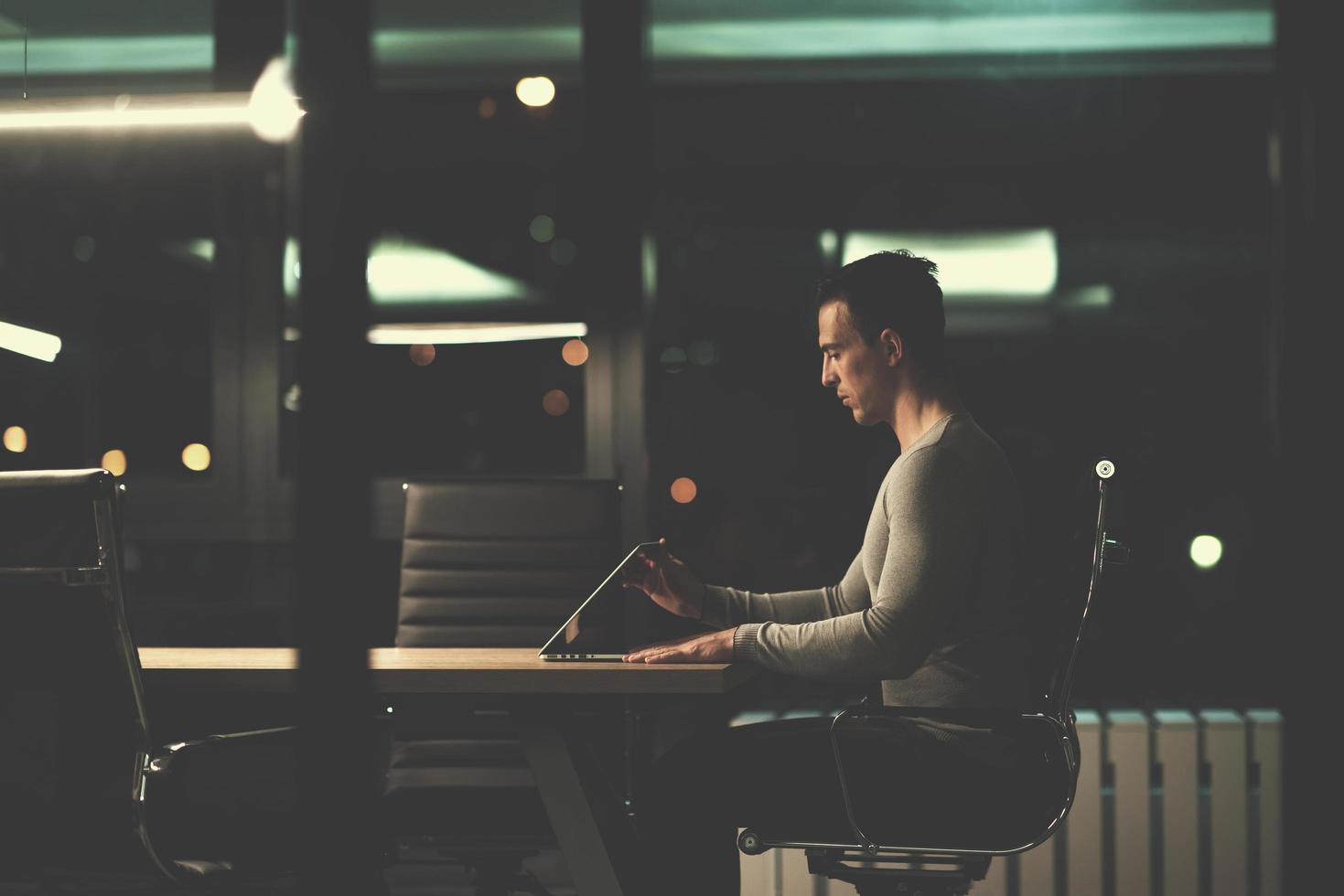 man working on laptop in dark office photo