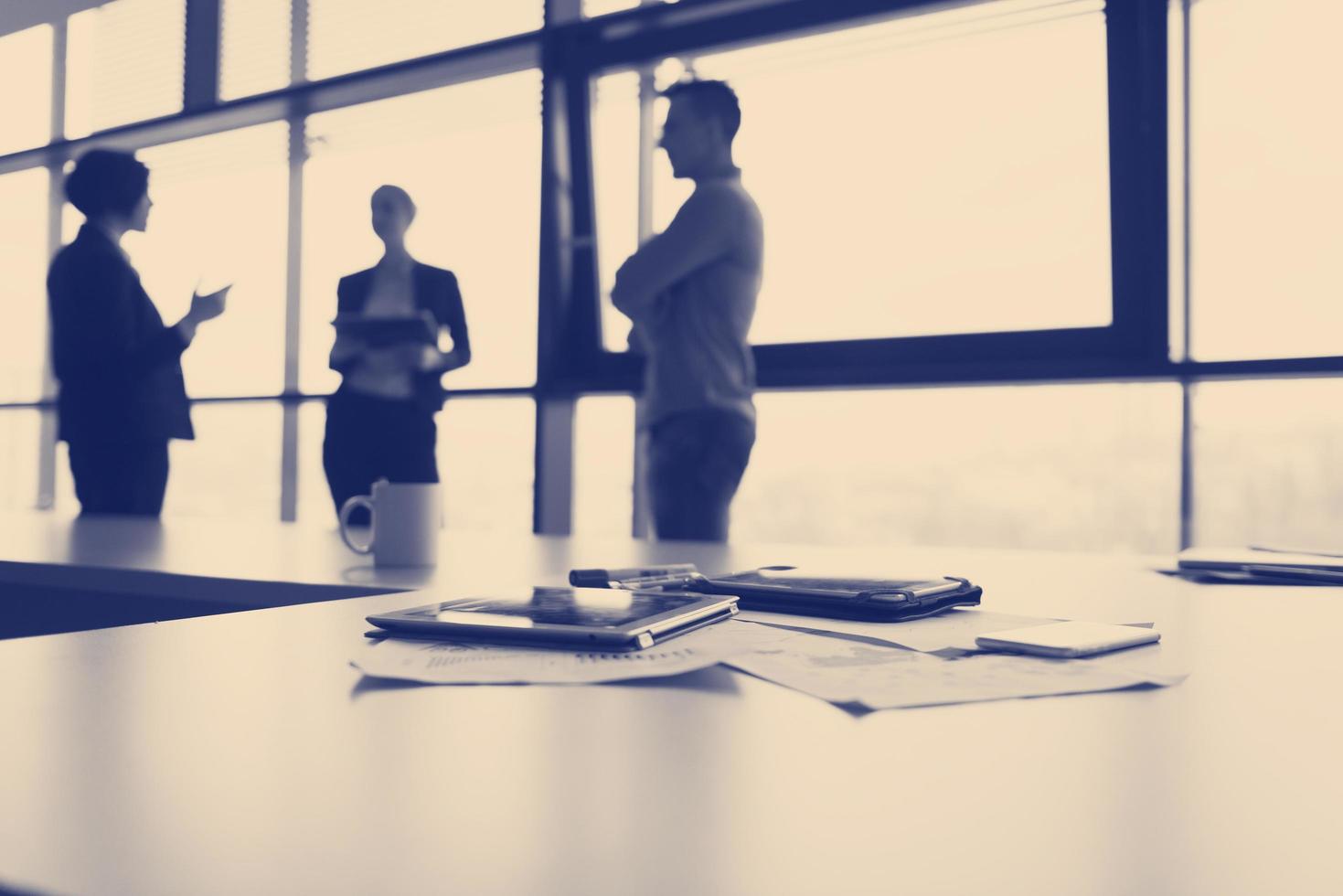close up of tablet, business people on meeting in background photo