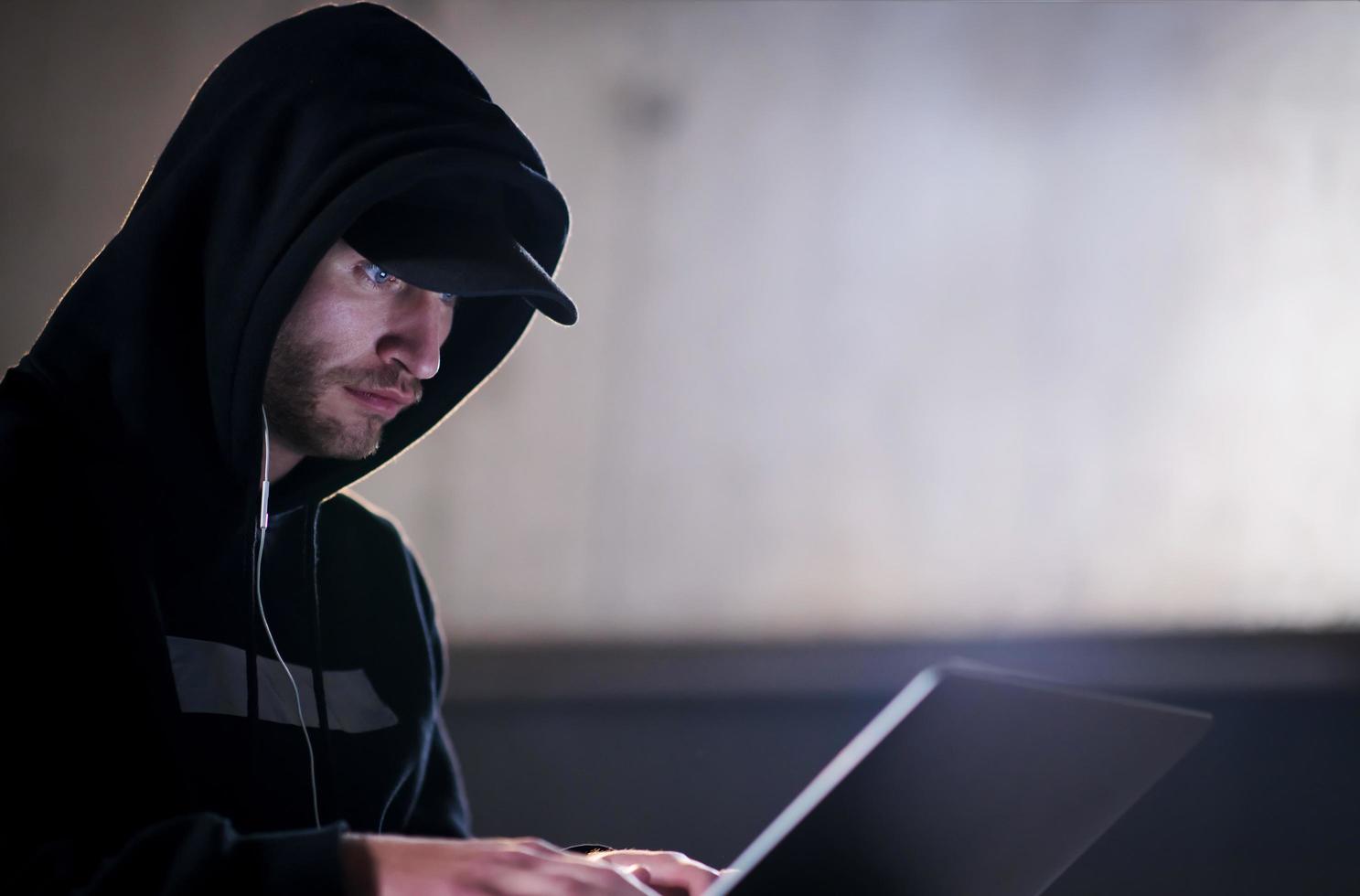 talented hacker using laptop computer while working in dark office photo