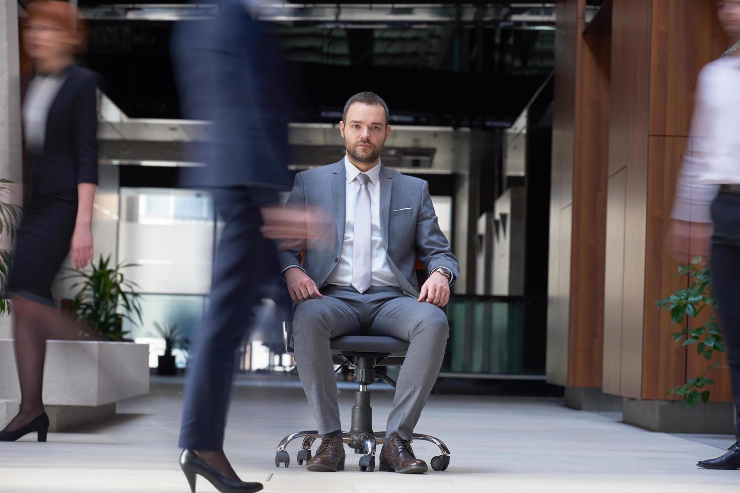 business man sitting in office chair, people group  passing by photo