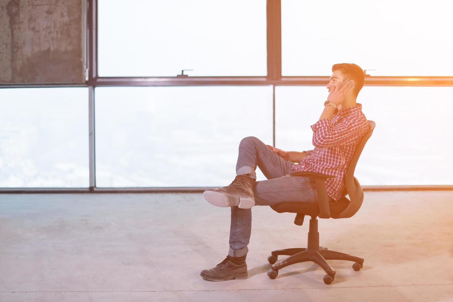 young casual businessman using mobile phone on construction site photo