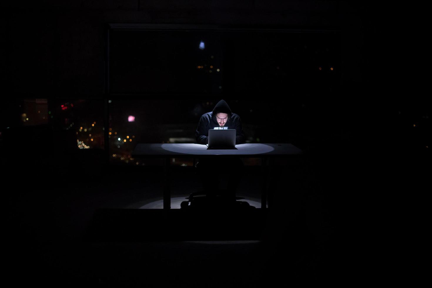 hacker using laptop computer while working in dark office photo