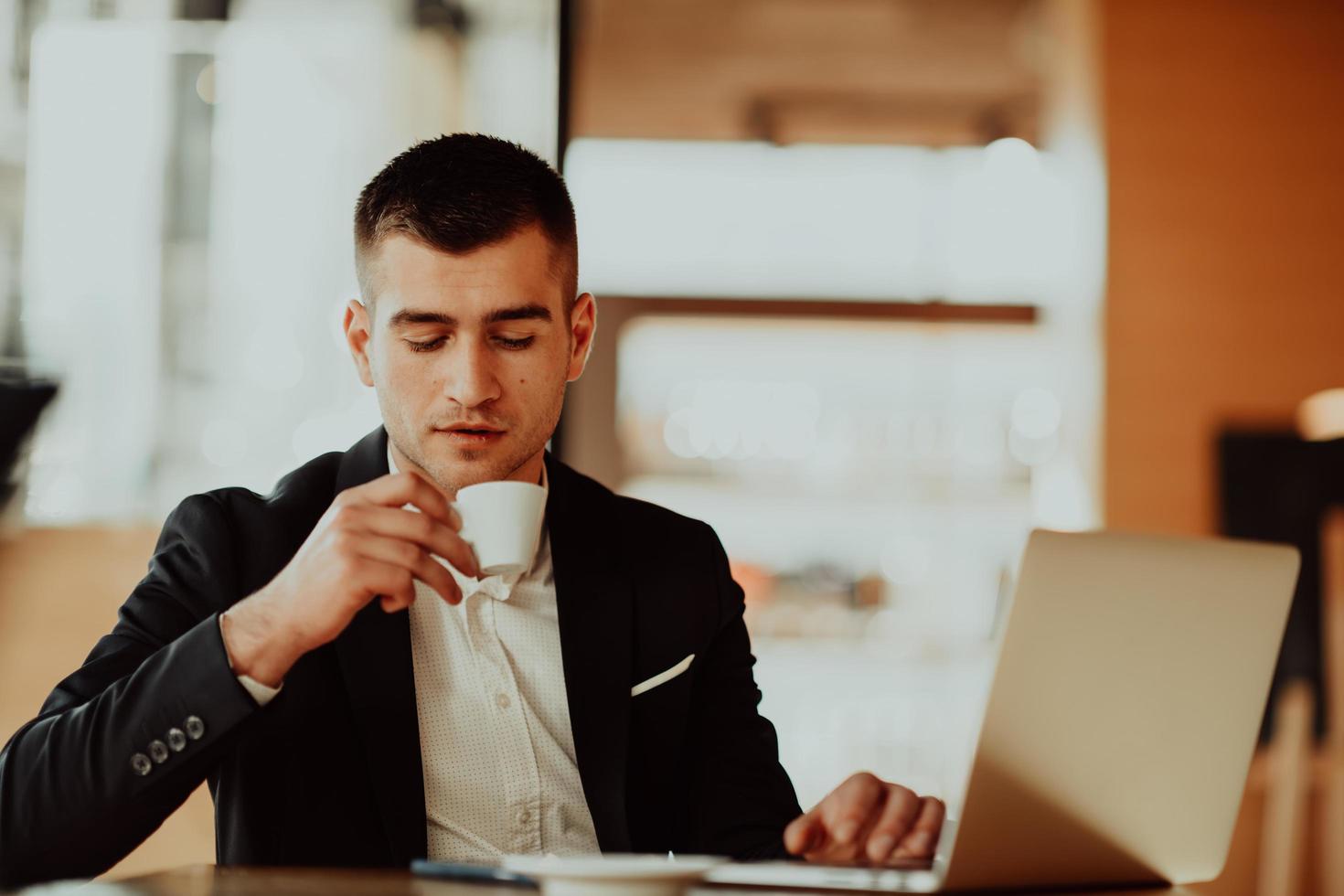 feliz hombre de negocios sentado en la cafetería con laptop y smartphone. foto