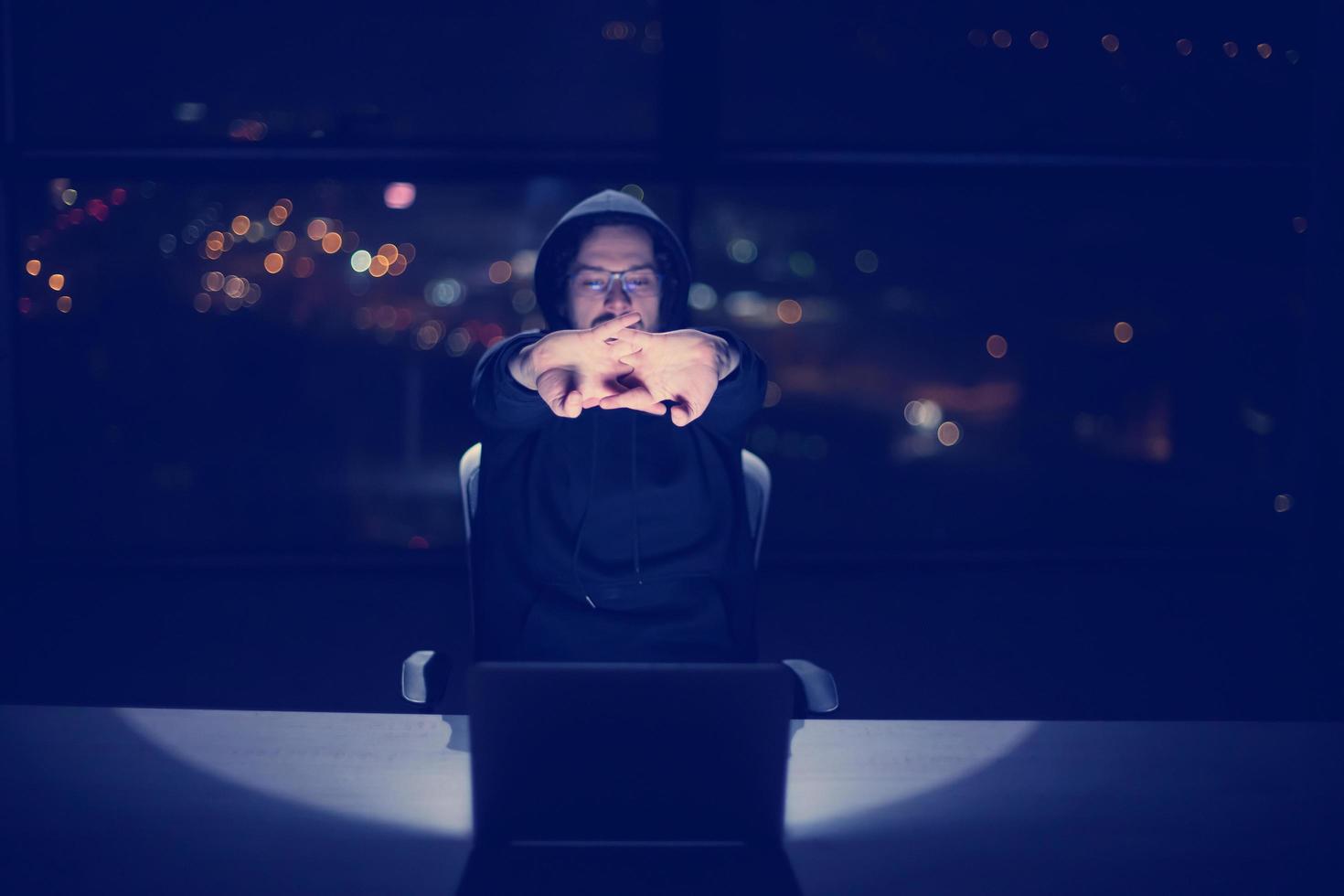 hacker using laptop computer while working in dark office photo