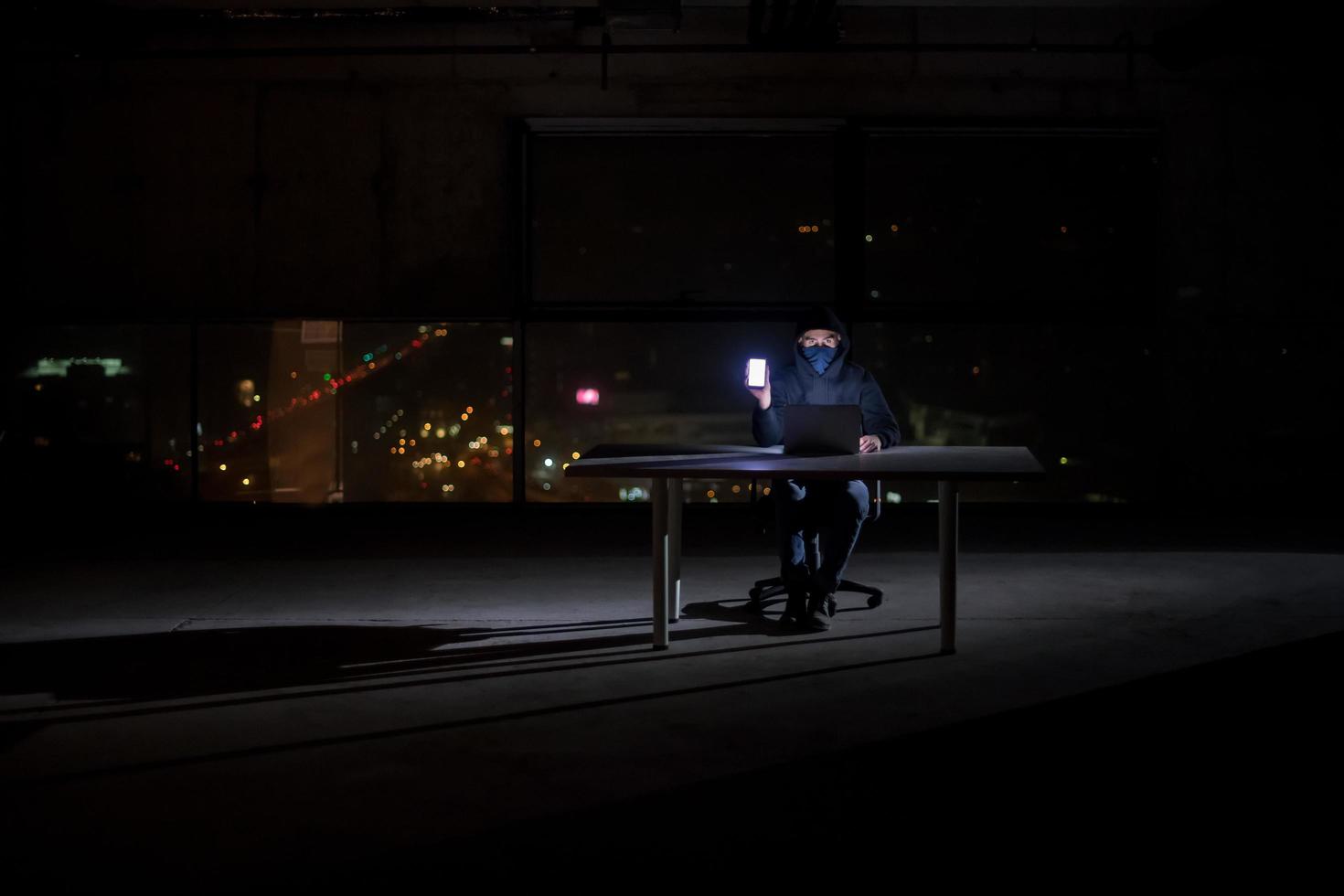 hacker using laptop computer while working in dark office photo