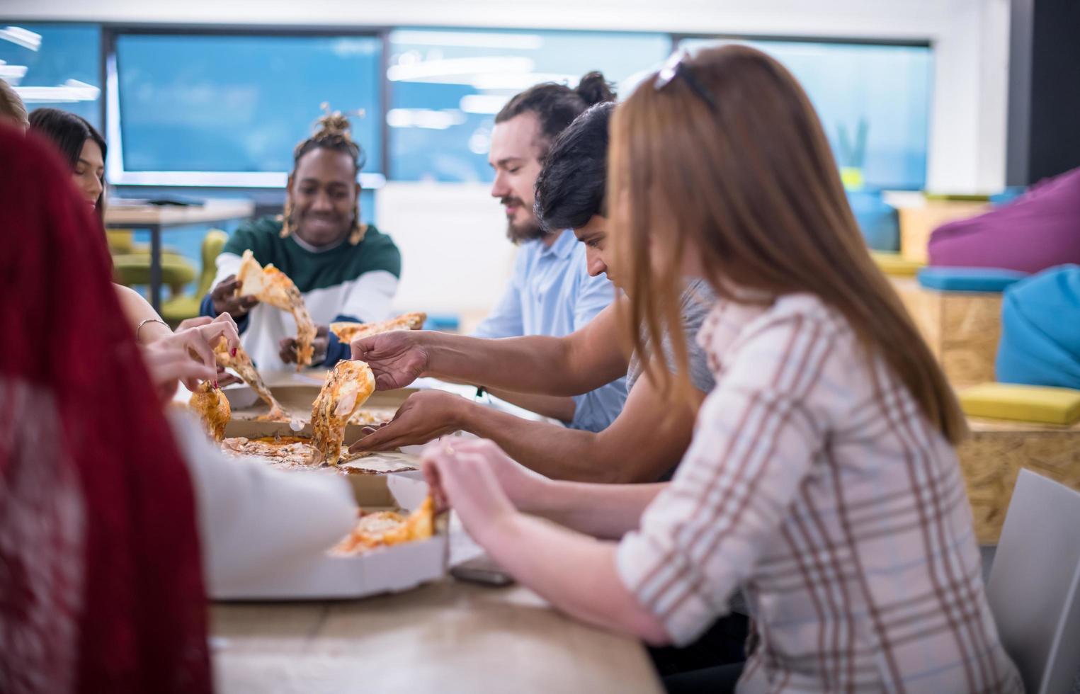 multiethnic business team eating pizza photo