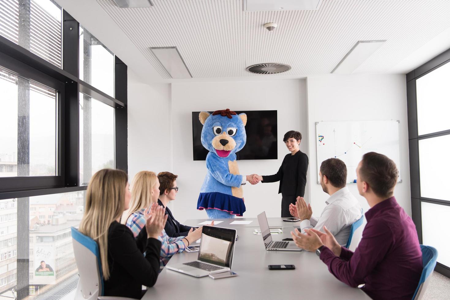 boss dresed as bear having fun with business people in trendy office photo