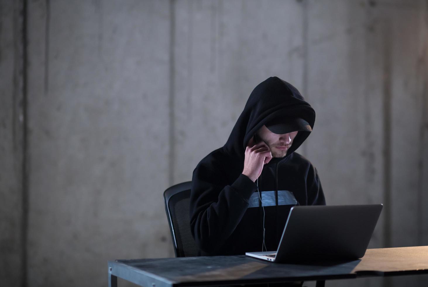 talented hacker using laptop computer while working in dark office photo