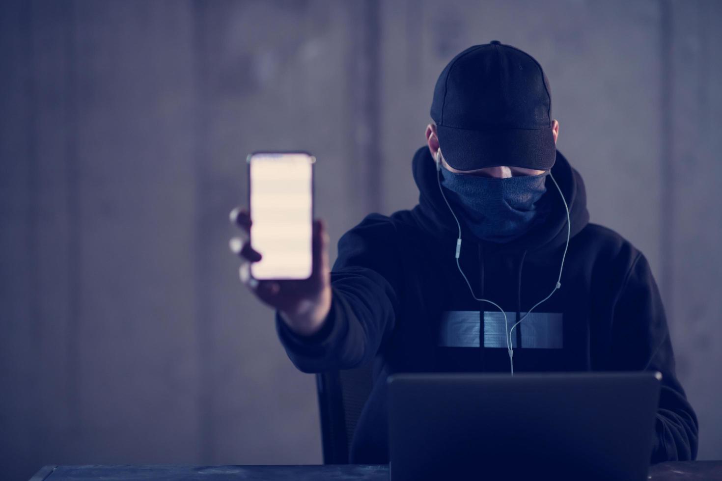 criminal hacker using laptop computer while working in dark office photo
