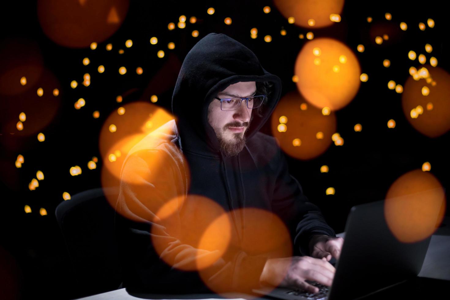 hacker using laptop computer while working in dark office photo