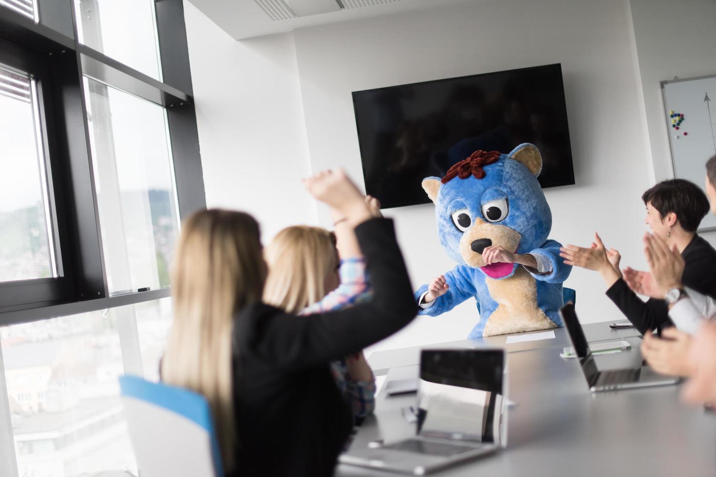 boss dresed as bear having fun with business people in trendy office photo