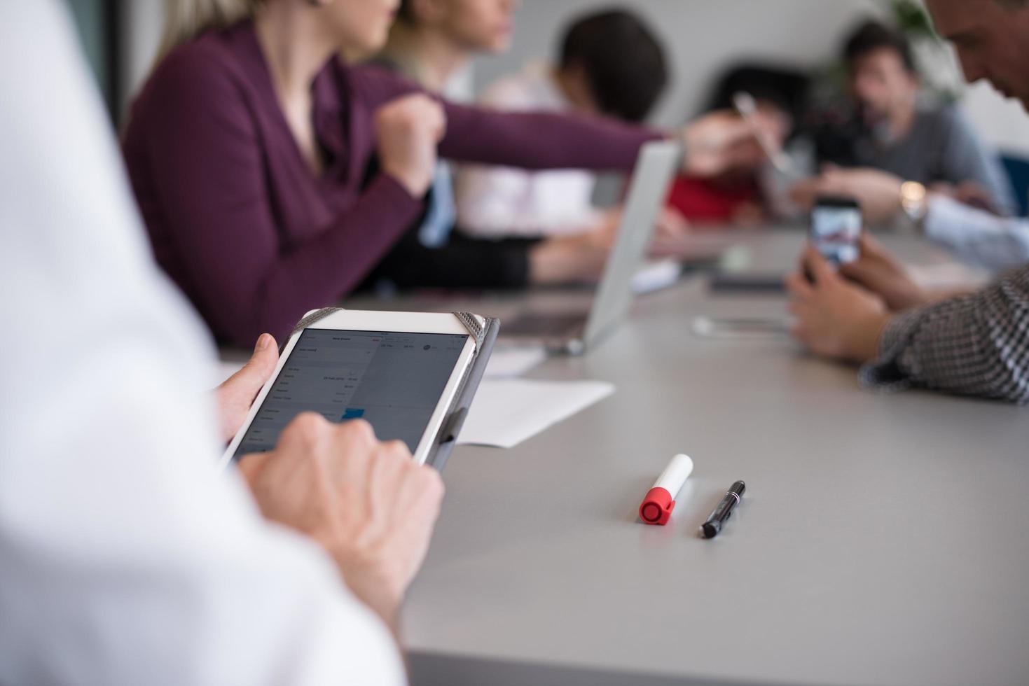 Cerca de las manos de un hombre de negocios usando una tableta en una reunión foto