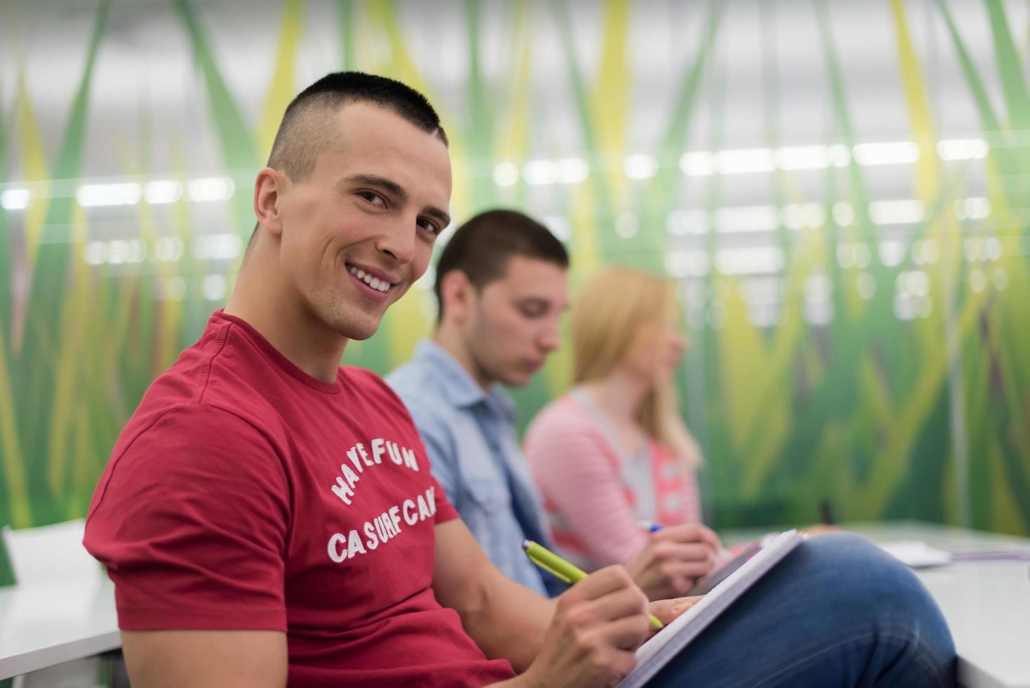 male student taking notes in classroom photo