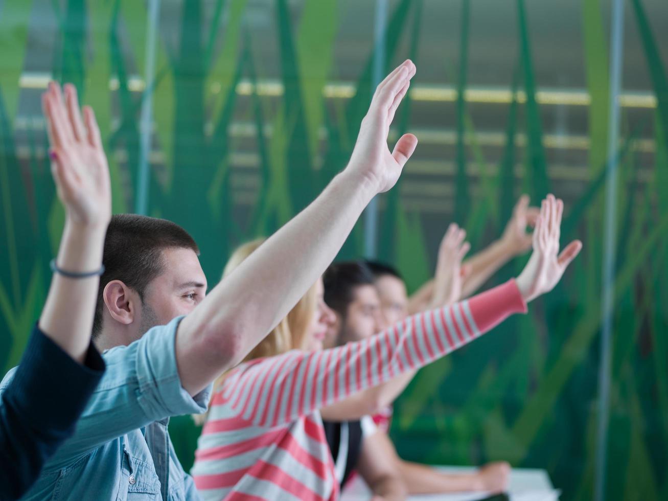 grupo de estudiantes levantan la mano en clase foto