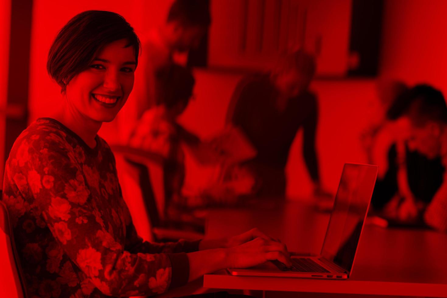 young business woman at office working on laptop with team on meeting in background photo